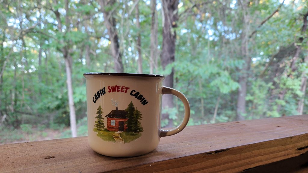 "Cabin Sweet Cabin" coffee mug overlooking nature scene at Mutton Creek Getaway